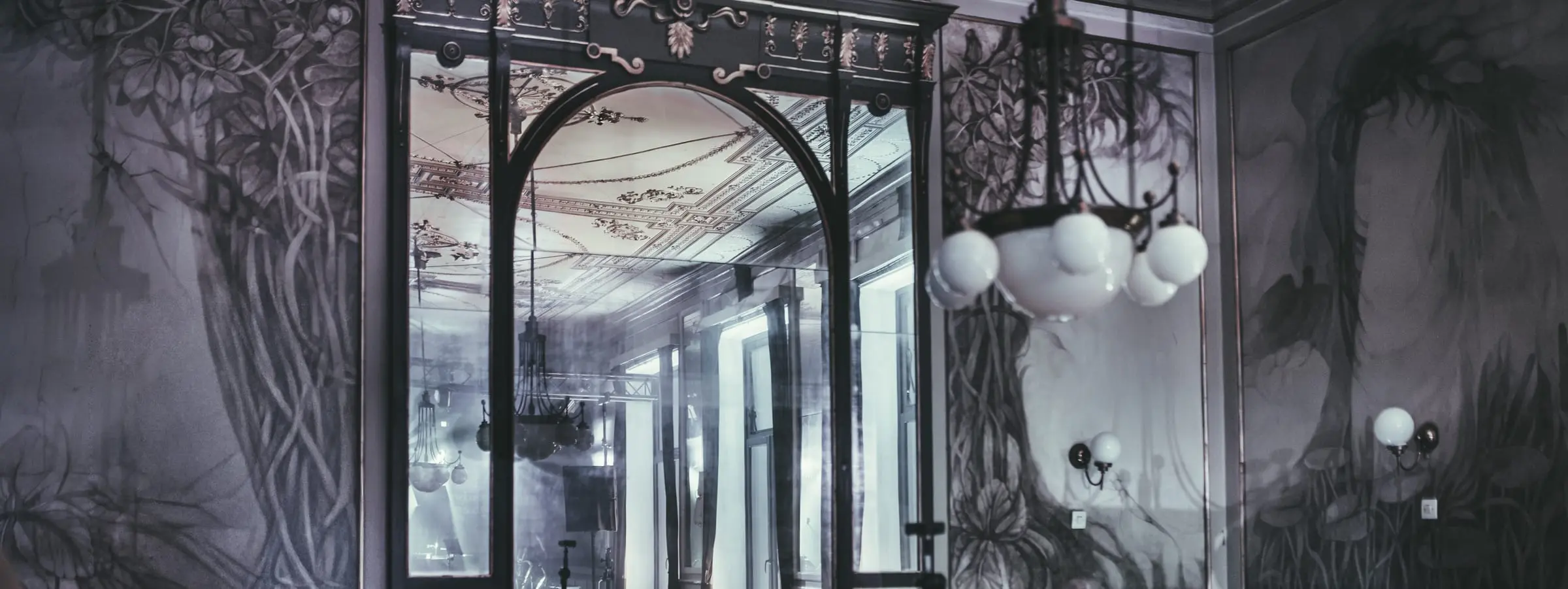 Łukowe okna, żyrandol i secesyjne malowidła w sali NovaPatria